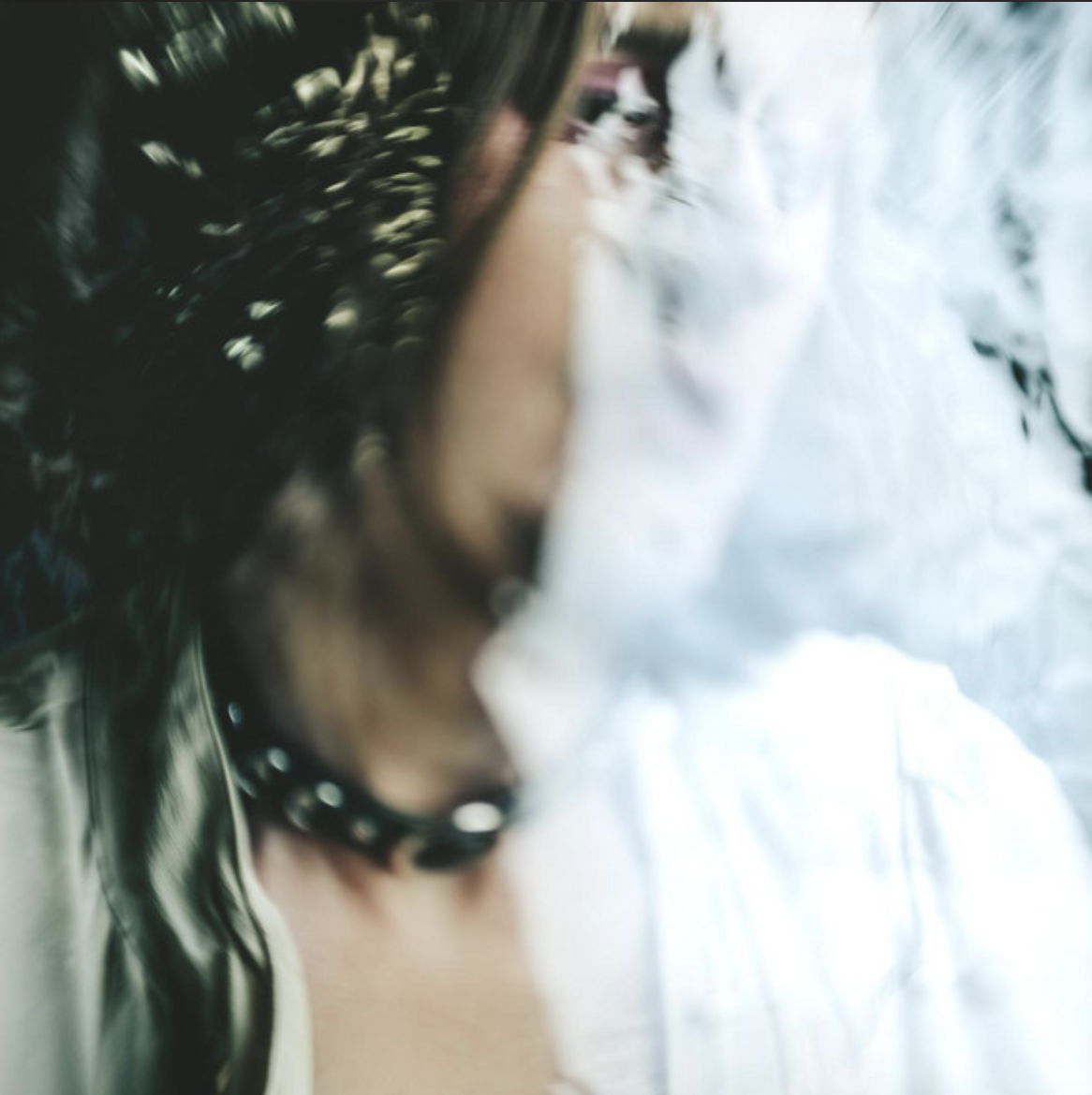 Artistic close-up portrait partially obscured by water and reflections with soft blue and green tones.