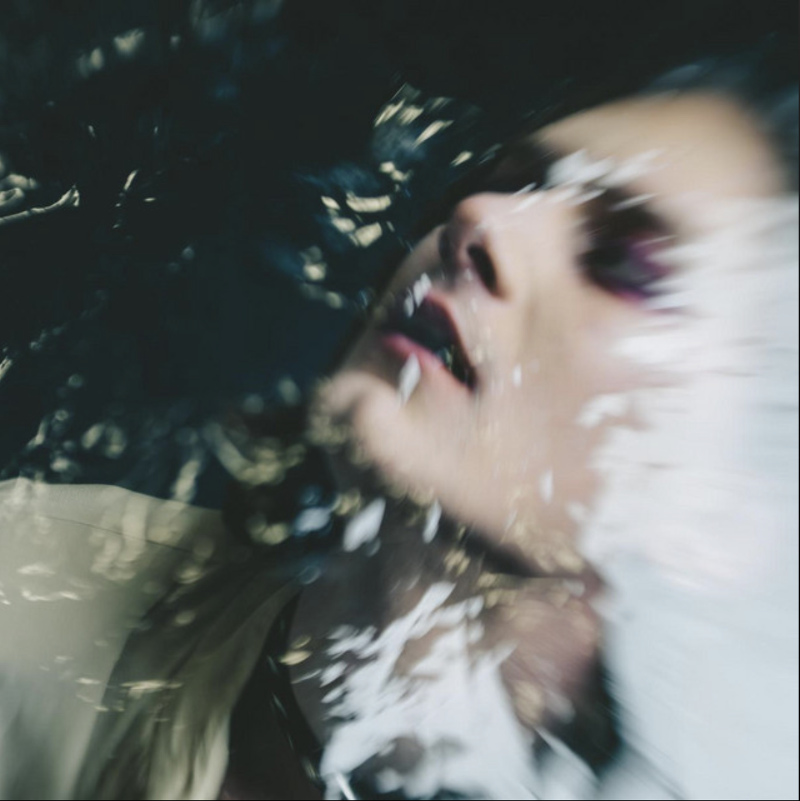 Dreamlike close-up portrait partially submerged in water with soft reflections and blurred movement.